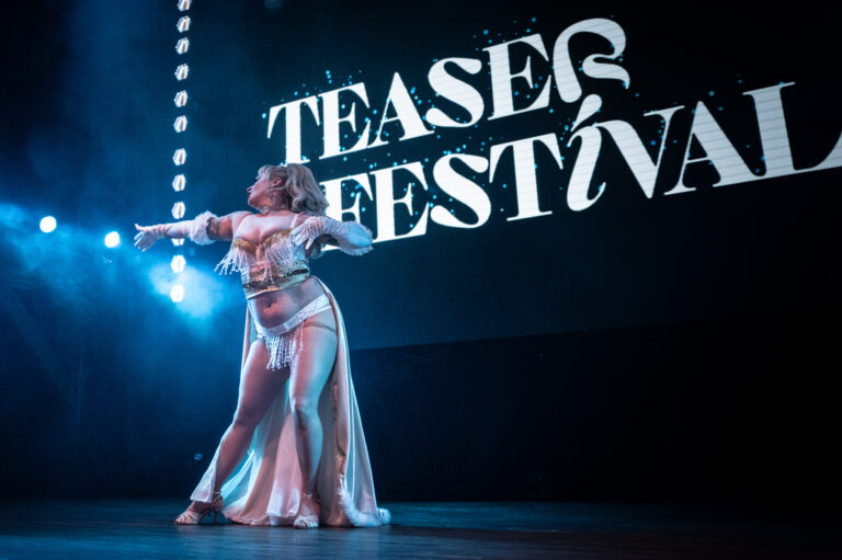 burlesque performer striking a pose in a gold and white costume